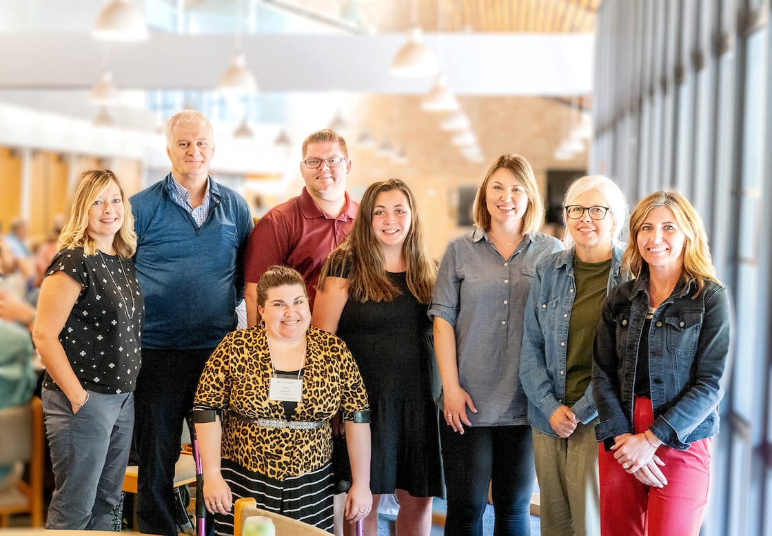 Eight people looking at the camera for a photo shoot inside a building